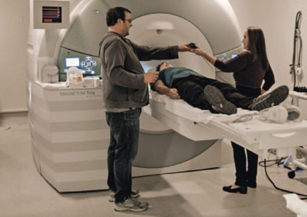 Techniker James Purl und Neurowissenschaftlerin Jane E. Joseph schieben Honnold in eine MRI-Röhre, um die Angstreaktion seines Gehirns zu messen. Nachdem er sich im
Tunnel grauenvolle und aufregende Bilder ansehen musste, meinte er lapidar: „Ich dachte, was soll das?“ Foto: NGC Network International